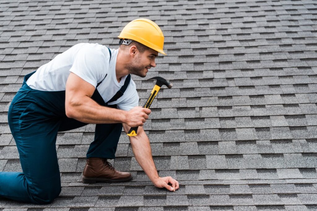 Handsome,Repairman,In,Helmet,Holding,Hammer,While,Repairing,Roof,In