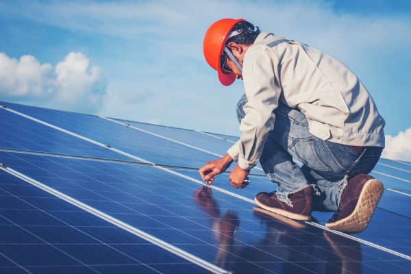 Un electricista trabajando en la reparación del panel solar por el panel de reemplazo