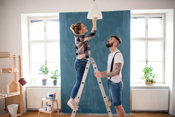Pareja de medianos adultos cambiando bombilla en casa, reubicación y concepto diy.