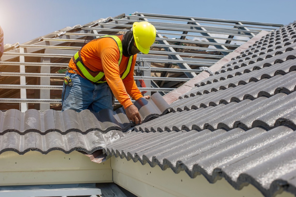 Roof repair, worker with white gloves replacing gray tiles or shingles on house