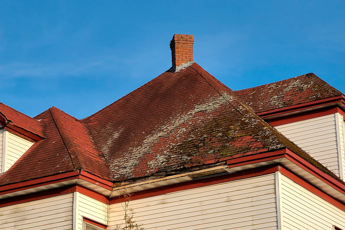 A red and white house topped with a clock, illustrating tips for safeguarding roofs against monsoon season mold.